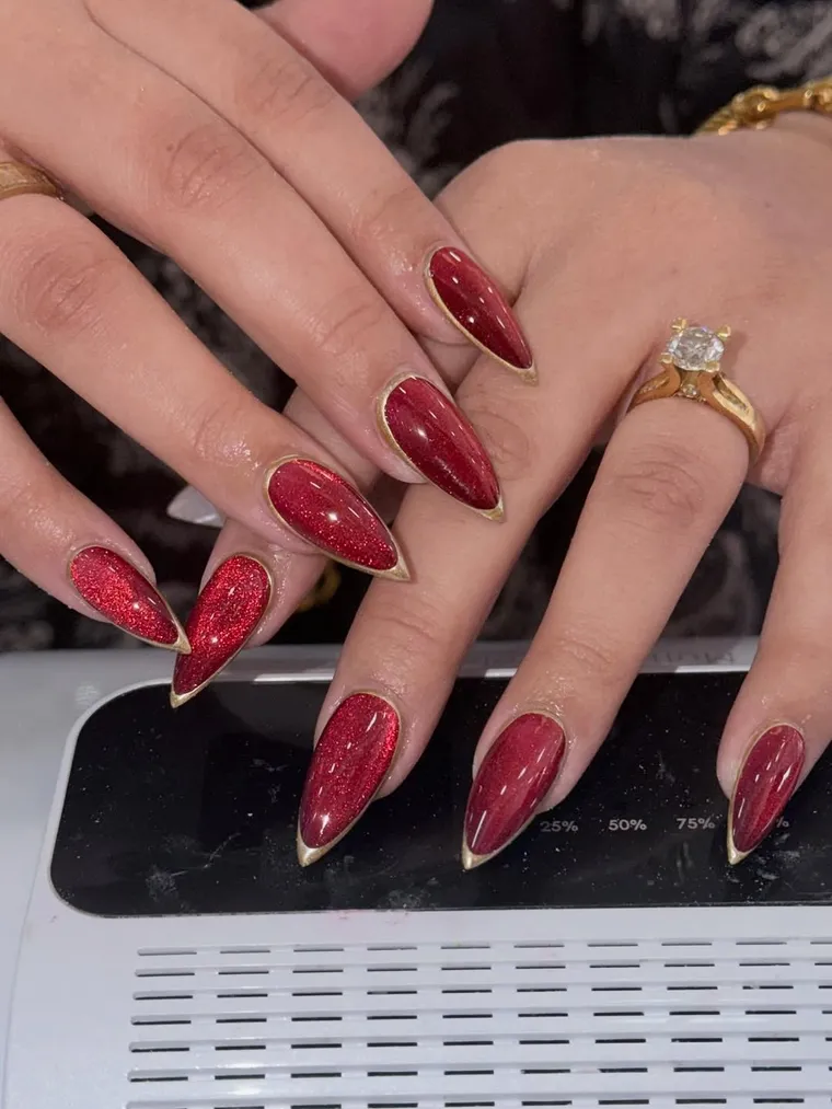 Red glitter cat-eye almond nails with gold edging, by JK Nails Chester