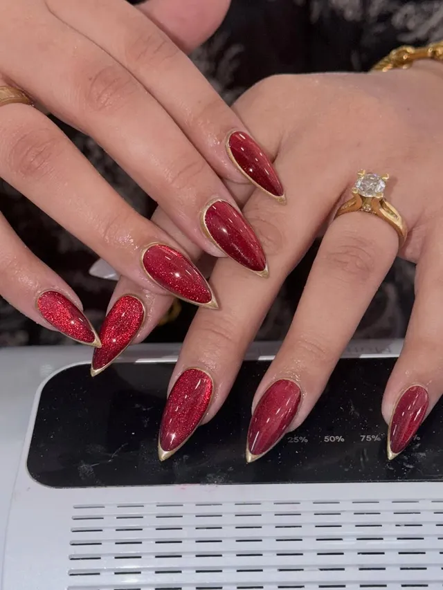 Red glitter cat-eye almond nails with gold edging
